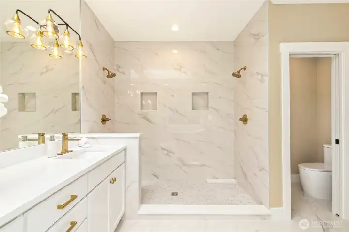 Luxurious primary suite w/ fireplace & spa-like ensuite featuring heated floors, freestanding tub, dual vanities & walk-in shower.