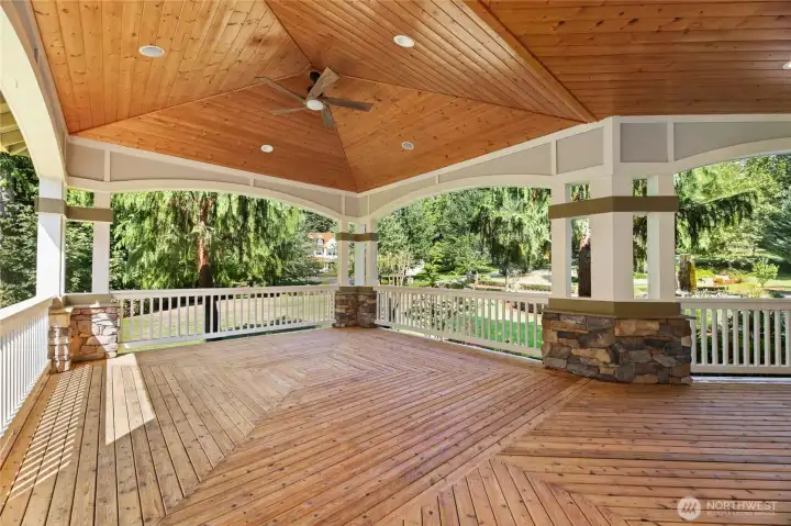 Newly refinished wraparound porch features rich wood flooring, crisp white railings, & serene views that invite relaxed outdoor living.