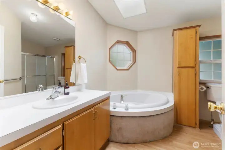 Primary suite features a jetted bathtub, walk-in shower, and large countertop vanity