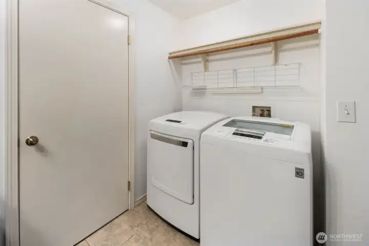 Main level laundry room within the 1/2 bathroom. Wood + wire shelving above washer and dryer.