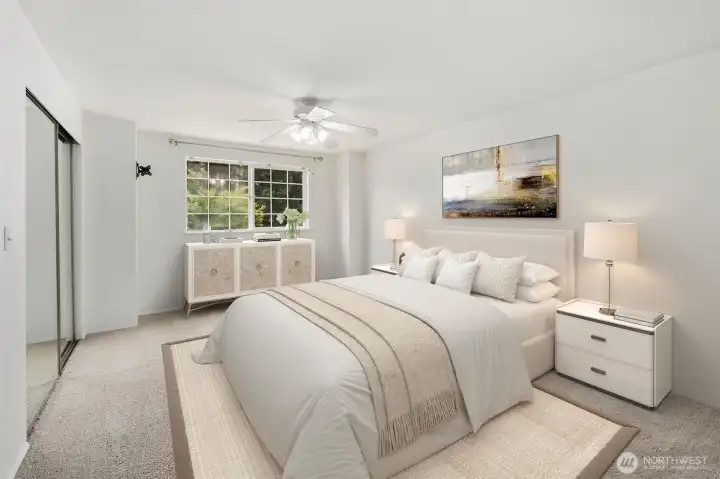 Virtually staged primary bedroom view from the door. Dual closets with mirrored doors on the left wall and one window facing the front of the home.