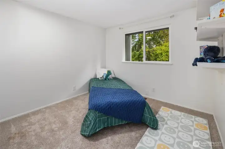 Upstairs bedroom with one window and 3 shelves on the right wall.