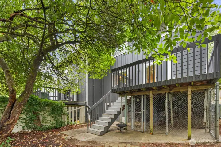 View of the back deck, stairs, and gated under-deck storage.