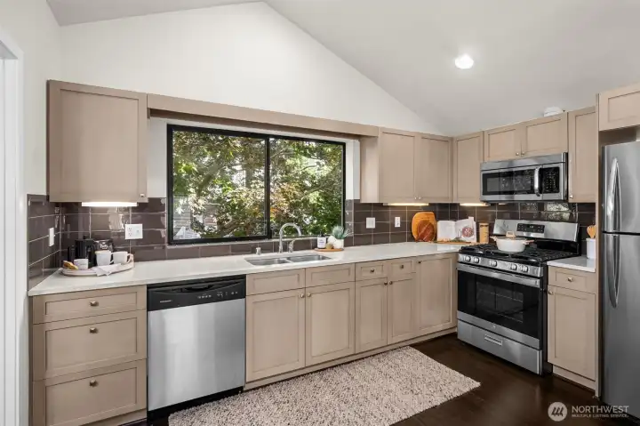 The kitchen features stainless steel appliances, quartz counter tops and glass-tile backsplash.