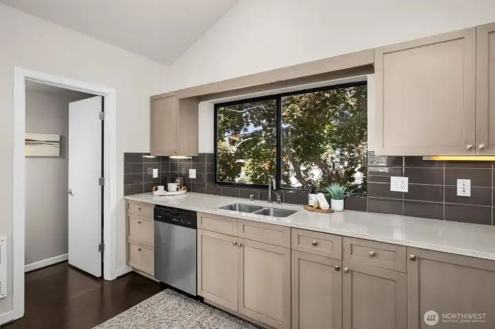 Another view of the kitchen with large window looking into the fully fenced backyard (1/2 bath to the left).