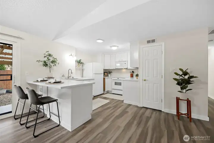 Kitchen with bar seating area, pantry closet off to the right of kitchen and sliding door out to the backyard to the left of kitchen next to dining room.