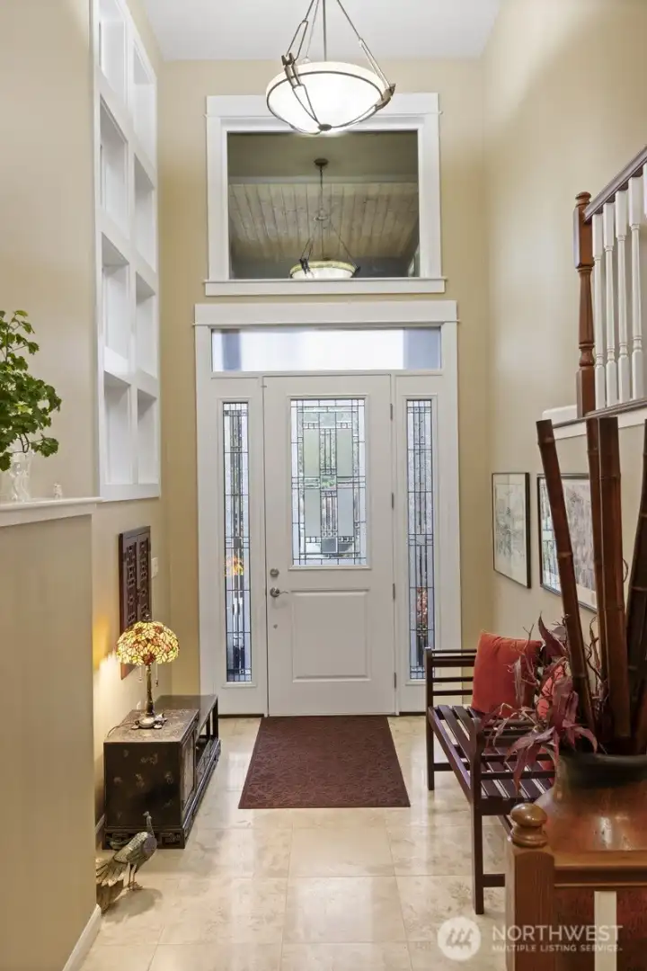 The welcoming entry is on its own level and has travertine tile flooring and soaring ceilings.