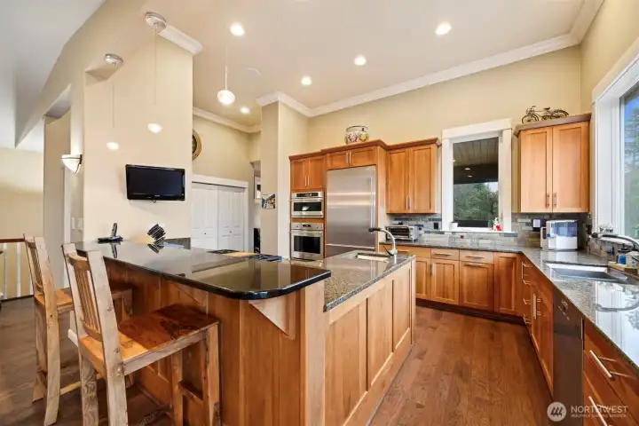 This stunning kitchen has an eating bar and a wall of pantry storage. There is a Monogram Collection wall oven, warming drawer and microwave just to the left of the Liebherr French door refrigerator.