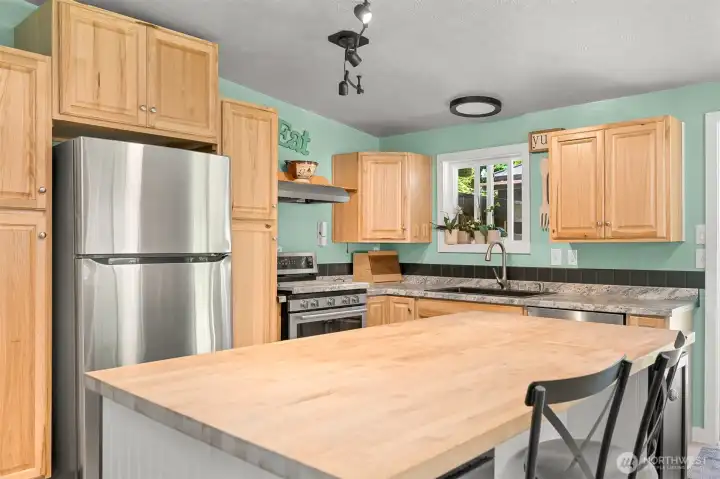 Updated kitchen featuring butcher block island, stainless steel appliances, and abundant natural light.