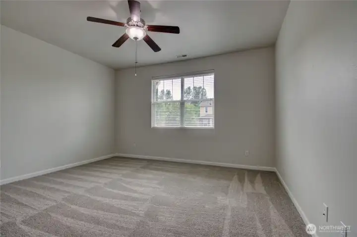 Primary bedroom with ceiling fan and new carpet.