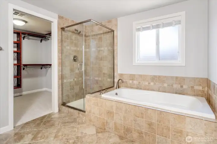 Primary bath featuring soaking tub, walk-in shower, and view of walk-in closet.