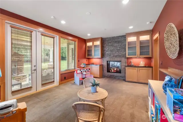 This double-sided fireplace connects the main living room to this flex room that has a wet bar and connects to outdoor living area thru the French doors.