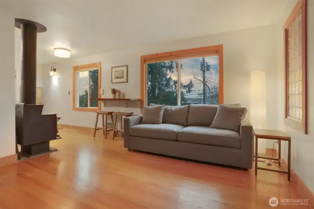 Main (South) home upper level living room with hardwood floors, bump out for entertainment center, woodstove and western exposure.