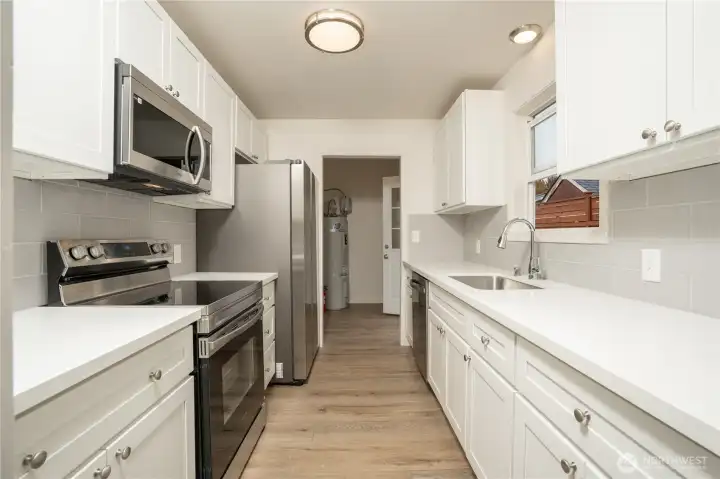 The kitchen is 100% updated with new soft-close cabinets, quartz counters, an undermount stainless steel sink, a tile backsplash, new LVP flooring, and new appliances.