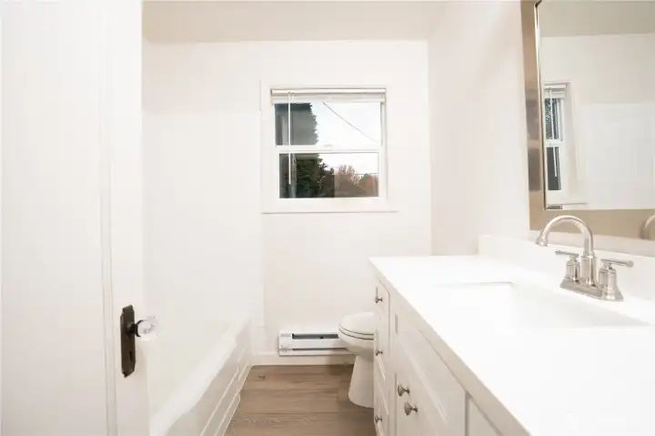 The bathroom is updated with an over-sized vanity with tons of storage, new fixtures, a new mirror, and all new flooring.