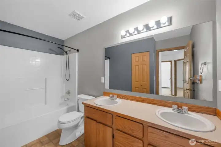 Hall bathroom with double sinks and linen