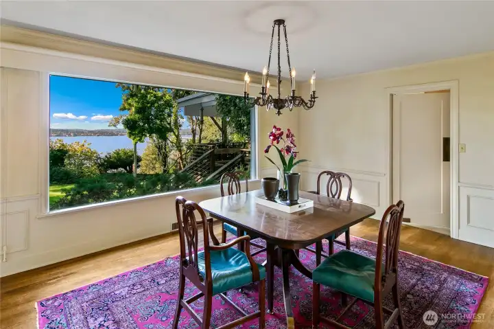 Framed by a picture window that captures sweeping views of the lake and lush gardens beyond, this elegant dining room is infused with light and serenity. Original millwork and a vintage chandelier add warmth and character, while the classic layout invites intimate meals and lively gatherings alike. It’s a space where the beauty of nature meets timeless design, inviting you to linger a little longer at the table.