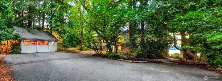 Nestled beneath a canopy of mature trees, the circular drive leads to a spacious motor court framed by a detached garage and the historic main residence. This serene, tree-lined arrival point offers ample guest parking and a quiet welcome to the heart of Evergreen Lakeshore Preserve—where timeless elegance meets the privacy of a forested retreat.