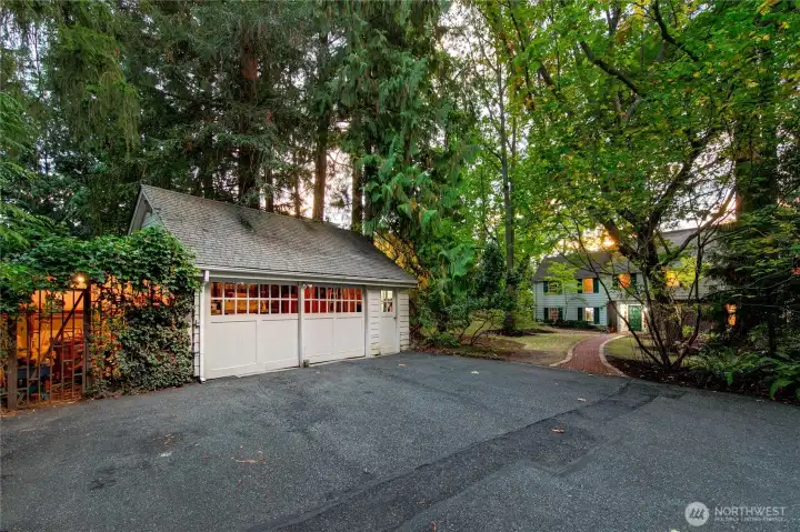 Flanked by towering evergreens and nestled into the woodland landscape, the detached garage offers convenient, covered parking while echoing the traditional architectural charm of the main home beyond. Its location near the circular drive provides ease of access while preserving the peaceful seclusion and natural beauty that define Evergreen Lakeshore Preserve.