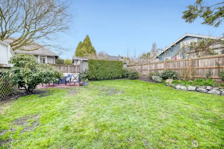 Big backyard with lots of grass and a patio.