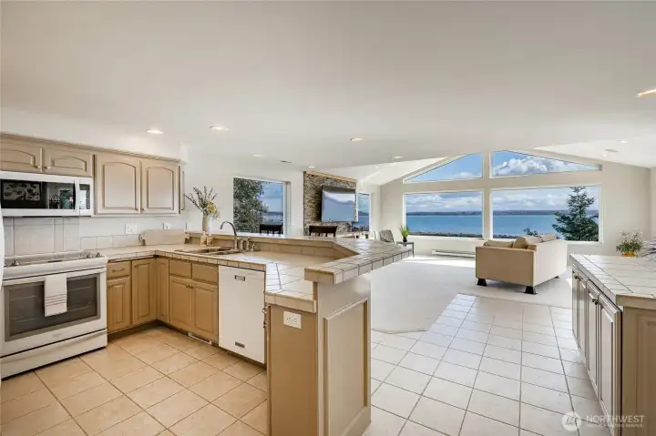 Tile floors and countertops in the kitchen area. Separate serving bar to your right. Light and bright in this home.