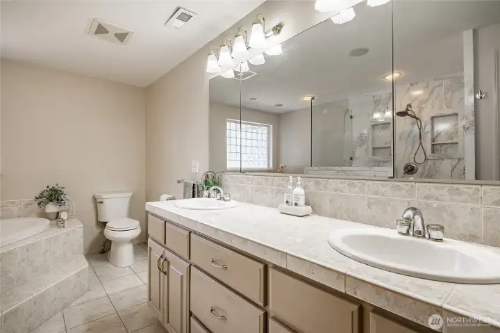 Primary bath with jetted tub, double vanity, tile counters and floors, shower with new glass surround.