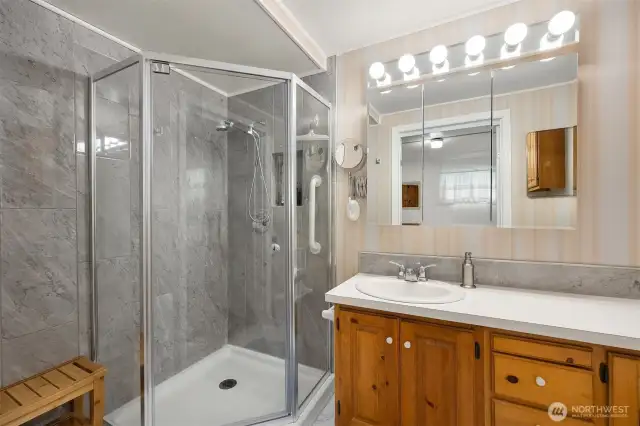 Bathroom off of bedroom with standing shower and ample counter/storage space.