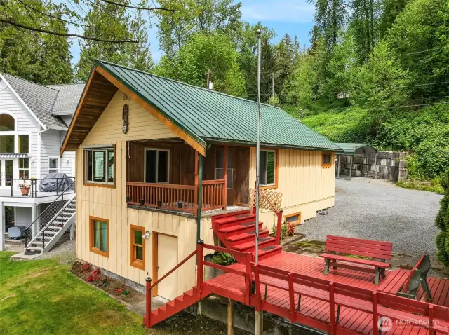 Front of home showcasing covered upper deck area, side deck, and access to lower level.