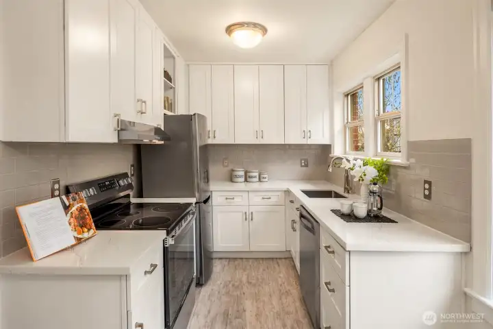 Recently updated kitchen that maximizes the space with cabinetry to the ceiling, a new range, quartz countertops, and a pleasant outlook while standing at the sink.
