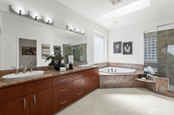 The primary bath with marble countertops, marble surrounded soaking tub, and generous shower.