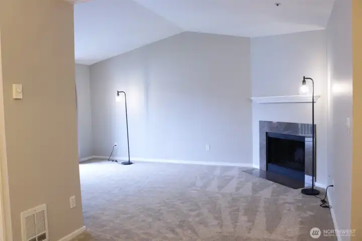 Living room with vaulted ceiling, fresh paint, trim moulding, and new carpet