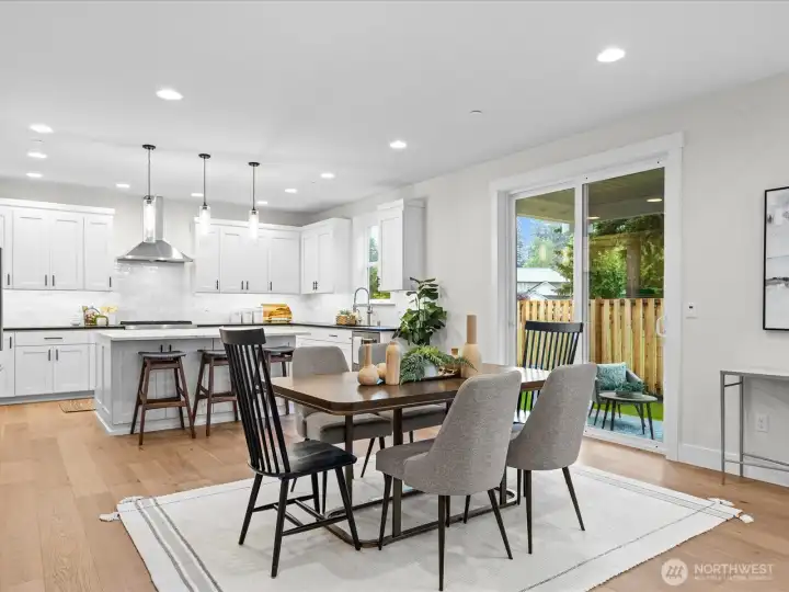 Casual eating space seamlessly flows into the gourmet kitchen, featuring modern finishes, bright recessed lighting, and a large sliding glass door that leads directly to the outdoor patio.