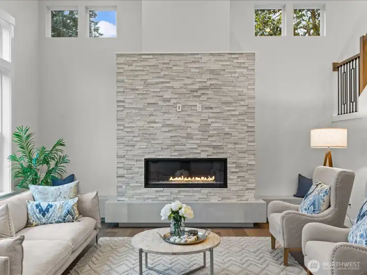 Cozy up to the linear gas fireplace, showcasing a beautiful floor-to-ceiling stone surround. A sleek, low-profile stone hearth adds modern texture while offering additional seating space in the heart of the Great Room.