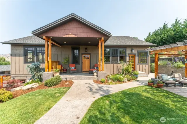 Welcoming craftsman-style entry framed by mature landscaping and timeless architectural details.