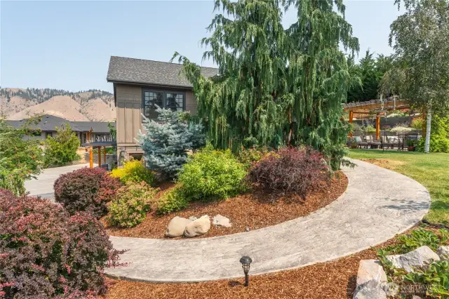 Graceful curved walkway leads through lush, manicured landscaping, creating a stunning approach to the home.