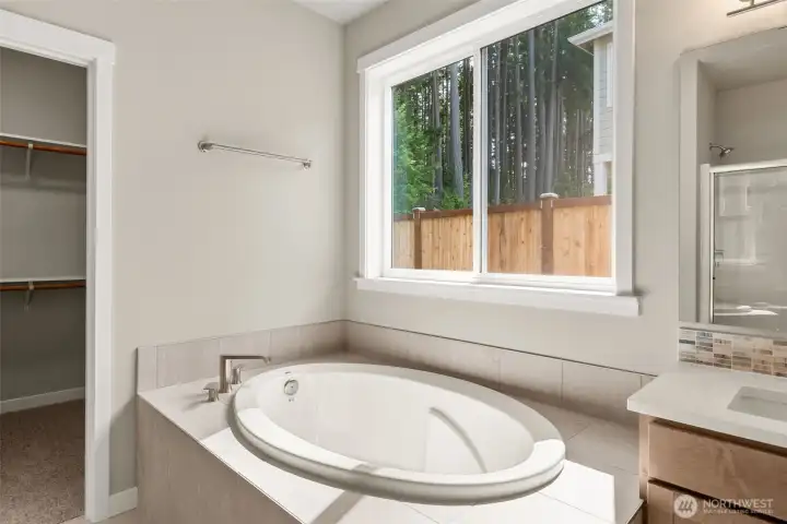 Primary bath also offers a beautiful, large soaking tub with tile surround.