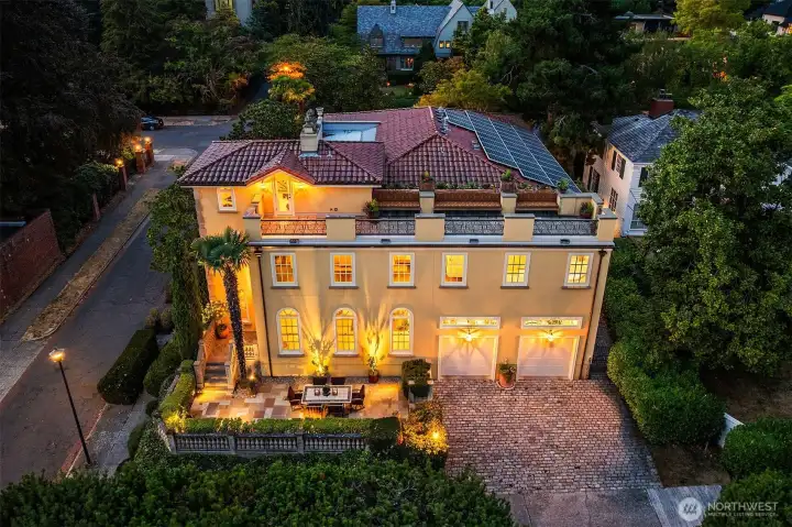 Aerial view of home's south exterior featuring terraced back patio, rooftop view deck, and tile roof with 9.4 kW solar array providing renewable power to the property.