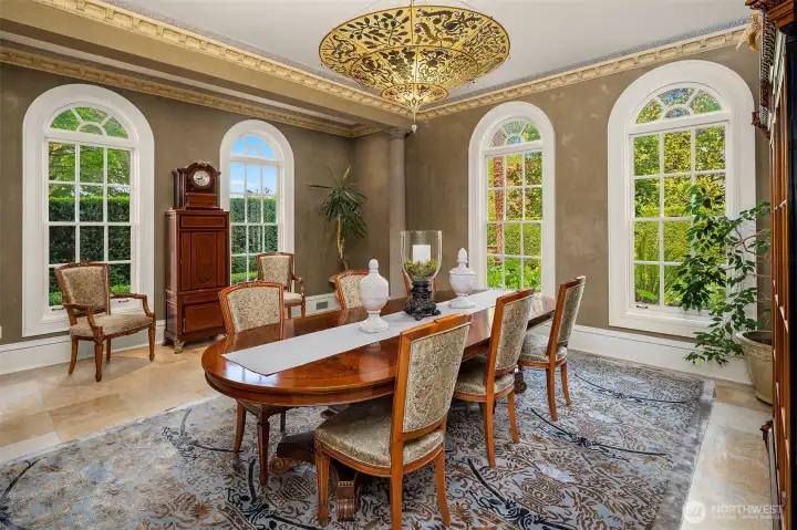 Gracious dining room with gorgeous silk Fortuny ceiling lamp and classic windows framing lush gardens and outdoor spaces.