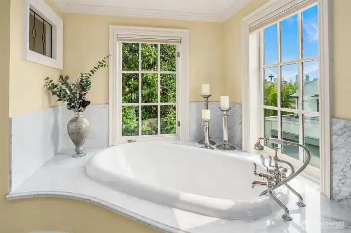 Fabulous soaking tub with handheld shower and Carrara marble surround – classic windows frame a view of the Space Needle.