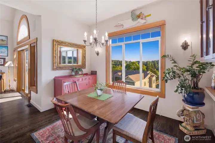 Elegant dining room features hardwood floors, a large south facing window with lush treetop views and a classic chandelier, making it an ideal space for intimate dinners or entertaining guests.