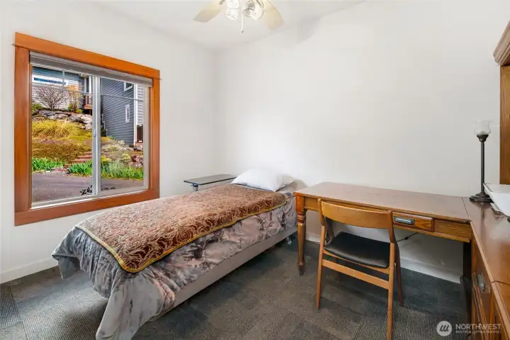 A well-proportioned secondary bedroom features a large window, closet, dark low-pile carpet, and versatile space suited for many needs.