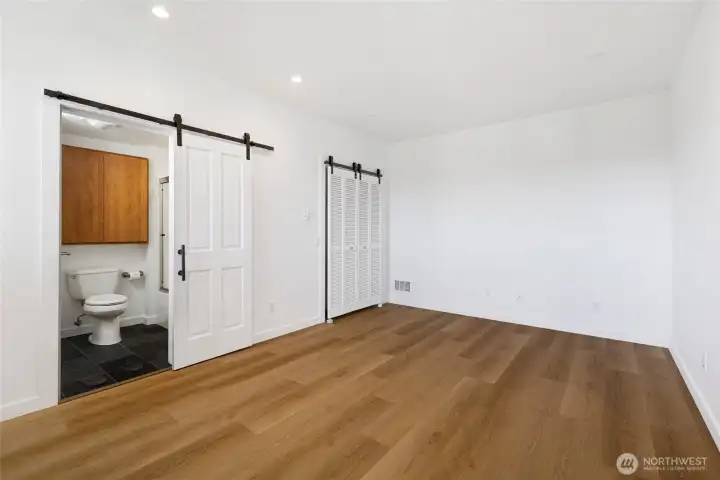 Spacious lower-level studio, leading to a well-appointed full bathroom and generous closet space. The clean white walls and abundant natural light create a bright, airy retreat. Perfect for guests, creative space or caregiver.