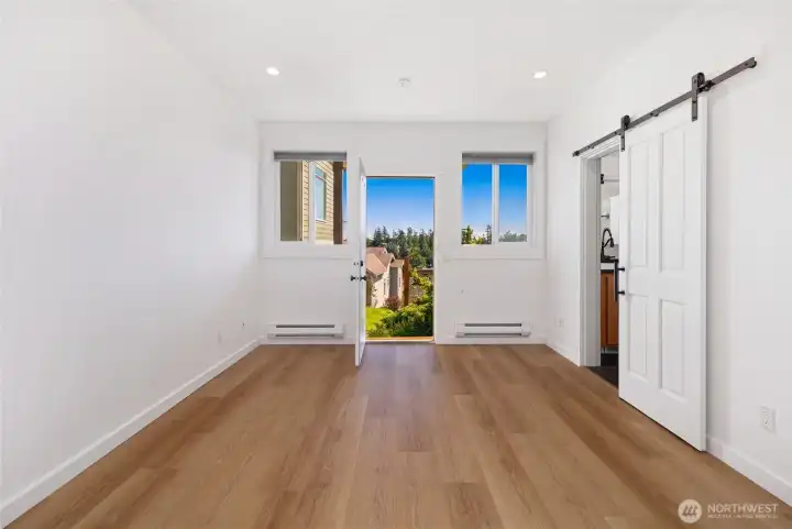 Light-filled lower-level studio boasts beautiful floors, a sliding barn door to the full bathroom, and direct access to a private patio framing stunning views of the surrounding island landscape. Baseboard heating and crisp white walls make this a versatile and inviting living space.