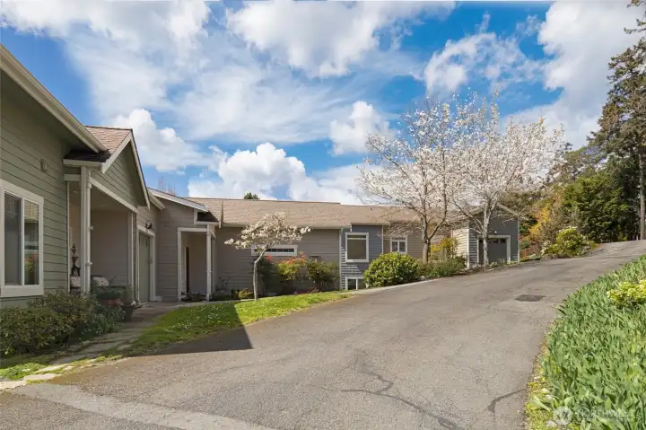 A peaceful private drive winds through this intimate enclave of well-maintained craftsman-style condos, surrounded by mature trees and beautifully landscaped common areas. The quiet, park-like setting offers residents a strong sense of community while maintaining privacy and tranquility.