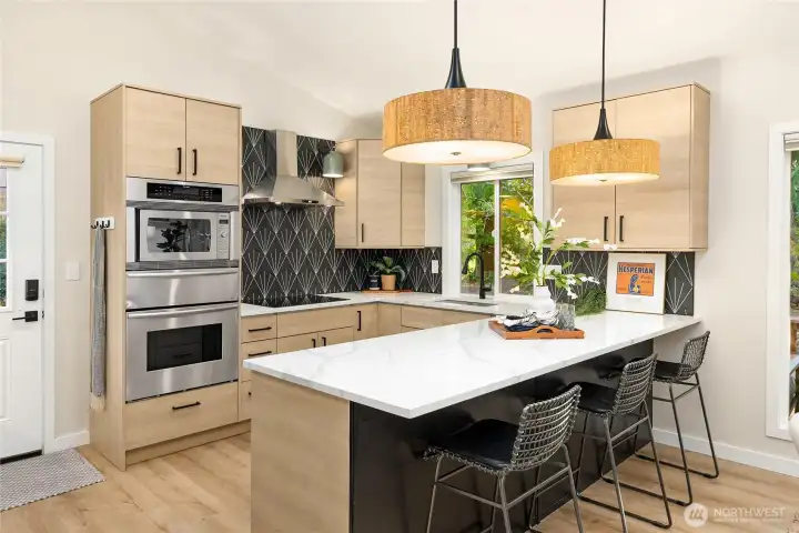 Stunning kitchen features quartz countertops, designer tile and lighting, and stainless Thermador and Samsung appliances