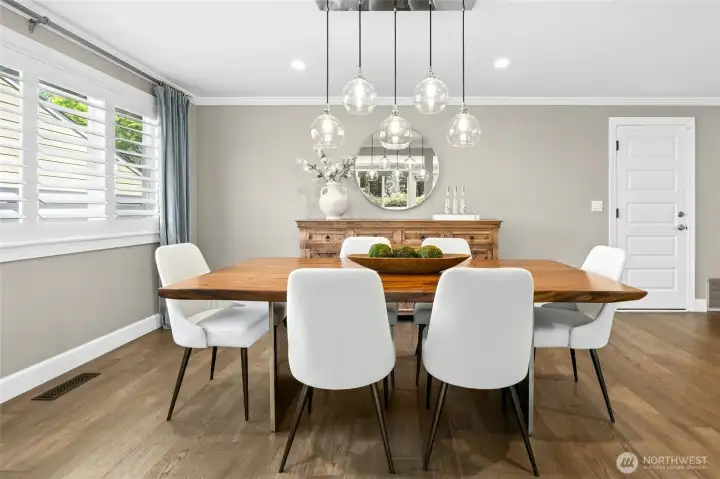 The dining room blends modern style with warmth, featuring plantation shutters, statement lighting, and clean, timeless finishes. Five panel doors, like the one on the right, have been added throughout the entire home.