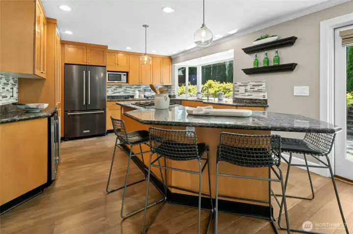 An oversized island with seating creates the perfect gathering spot for casual mornings, homework sessions, or conversation while cooking. Handy beverage fridge (on left) is an easy reach for thirsty individuals ready for libations.