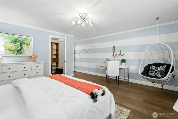 This spacious main floor bedroom features a playful hanging chair, custom light fixture, and a large walk-in closet with built-in organization.