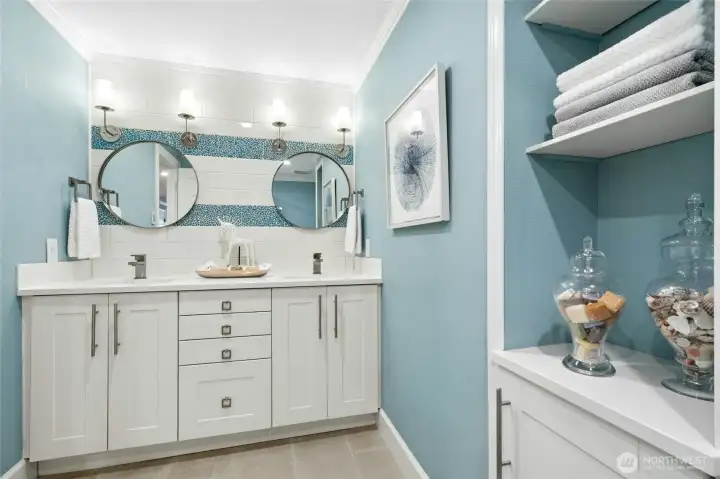 The main-floor hall bath is beautifully updated with dual sinks, modern finishes, and striking designer tile accents that add a fresh coastal-inspired feel.
