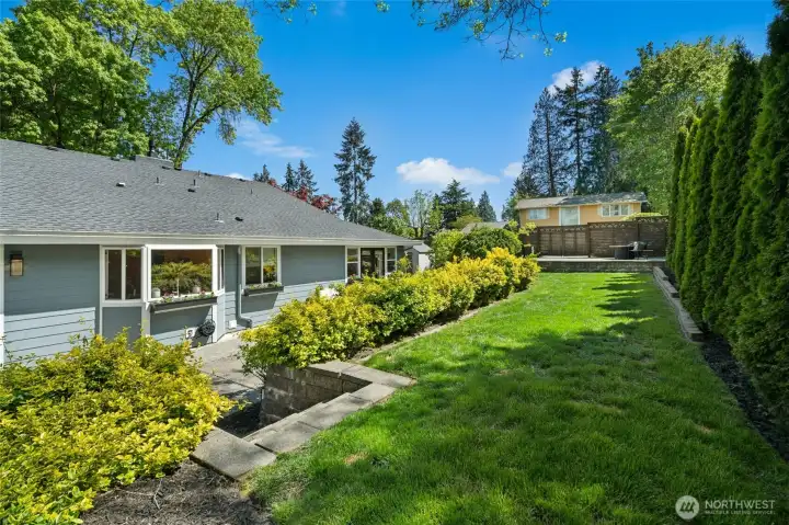 The upper terraced level adds another layer of usable outdoor space, with a broad lawn, mature privacy screening, and elevated gathering areas woven into the landscape design.
